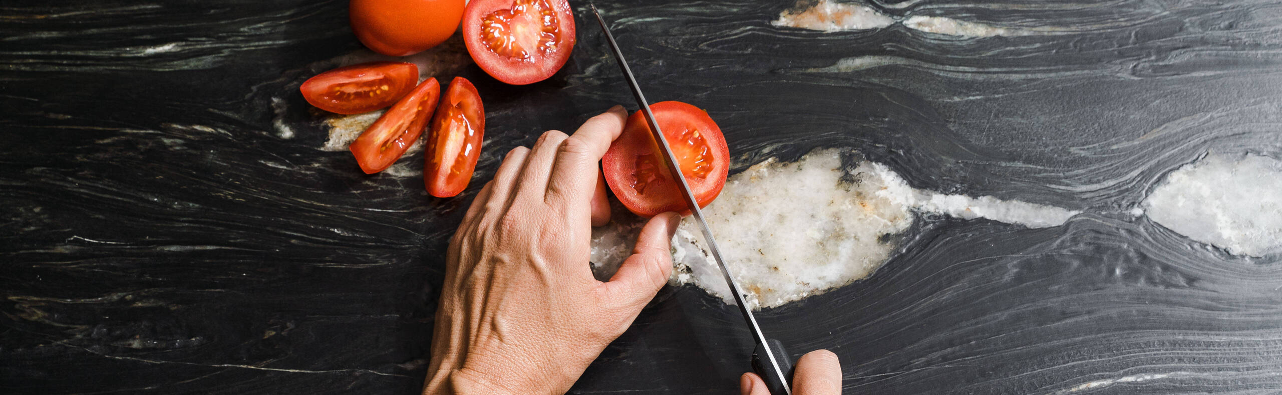 Tomaten werden auf einem Küchentisch geschnitten